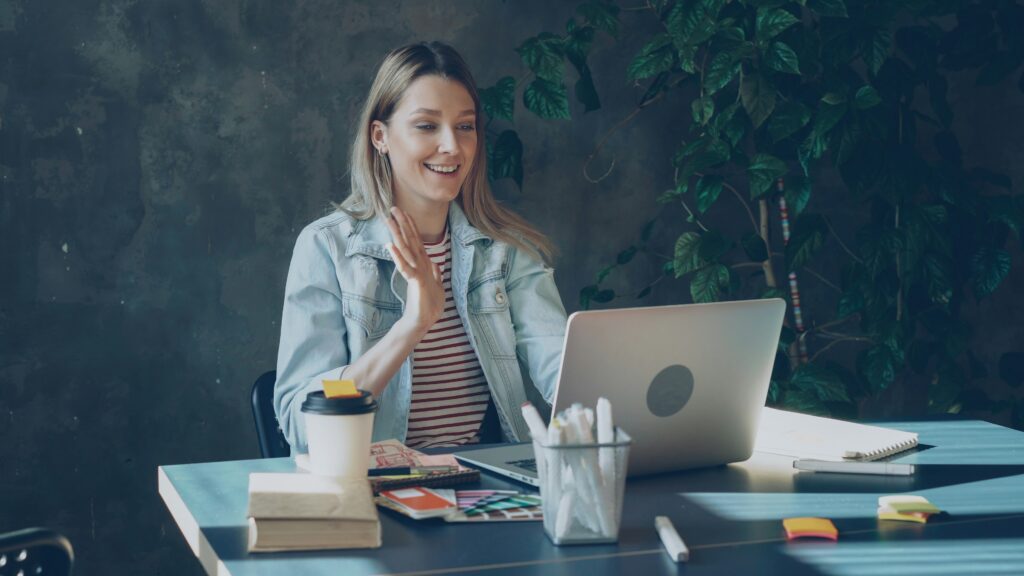 vitaly gariev nsj0hdqurw0 unsplash woman waves at screen meeting others in an online entrepreneur community