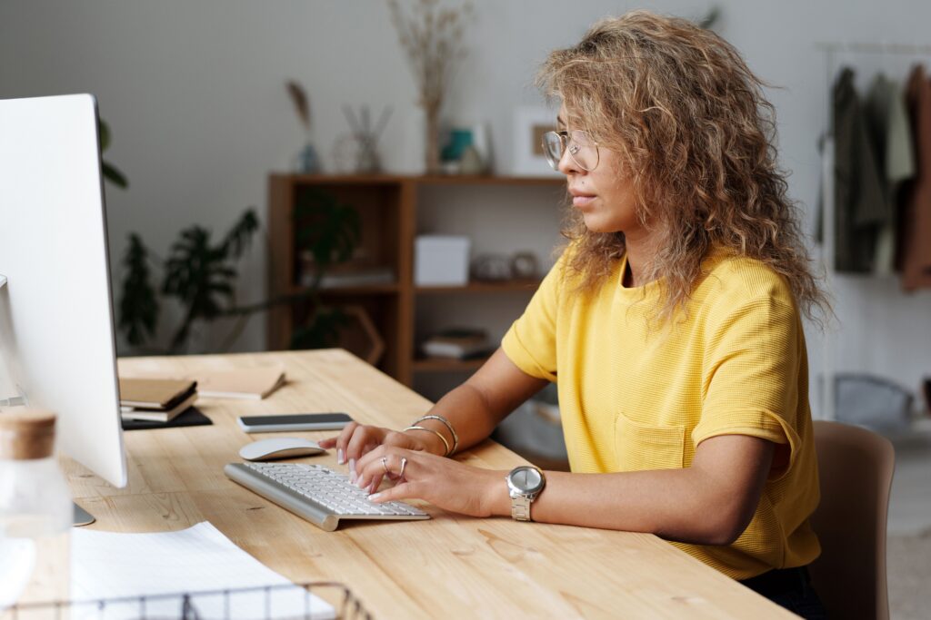 pexels photo 4175328 4175328 A woman working remotely from home, typing on a keyboard at her work desk.