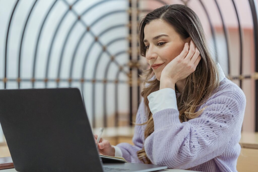 pexels photo 6953962 6953962 Smiling female teleworker leaning on hand while taking notes in planner during remote work at looking at screen