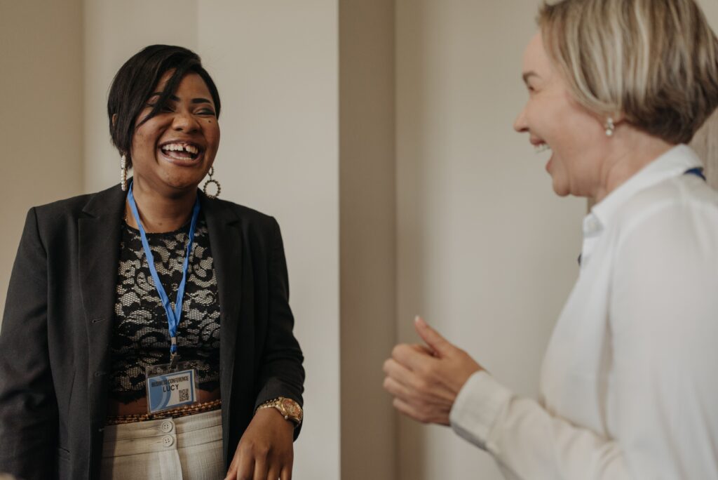 Two women sharing a joyful moment in a business meeting setting, fostering teamwork.
